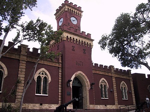 The front of red brick building with yellow trim. There are arched windows and a door.