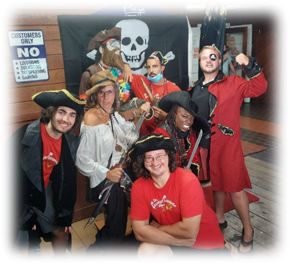 People in Tropical Treasure Hunt gear and pirate costumes pose on the beach.